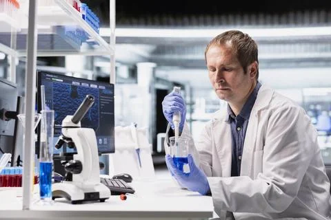Scientist uses pipette to mix elements in jar for biotechnology research Stock Photos