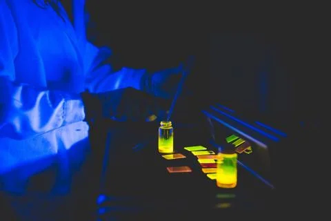 Scientist using fluorescence lamp, checking the fluorescence of different Foto stock