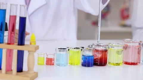 Scientist Using Glass Pipette to Mix Colorful Liquids in Laboratory Beakers Stock Footage 340190668