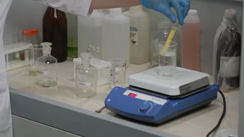 Scientist Using Magnetic Stirrer for Liquid Mixing in Lab Stock Footage 306319311