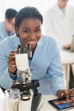 Scientist using microscope and digital tablet in research laboratory Stock Photos