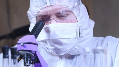 Scientist using a microscope and enters data into a computer in laboratory. Stock-Footage 122764261
