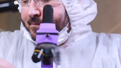 Scientist using a microscope and enters data into a computer in laboratory. Stock-Footage 122764822