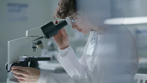 Scientist Using Microscope and Turning Focus Knob during Examination Stock Footage 304762929