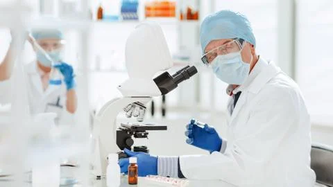 Scientist using a microscope in a biochemical laboratory. Stock Photos