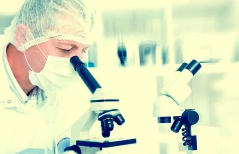 Scientist using microscope with dna image in background Foto stock