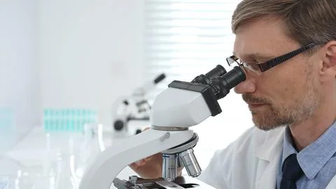 Scientist using a microscope is doing scientific research in a modern laboratory Stock Photos
