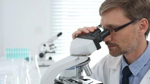 Scientist using a microscope is doing scientific research in a modern laboratory Stock Photos