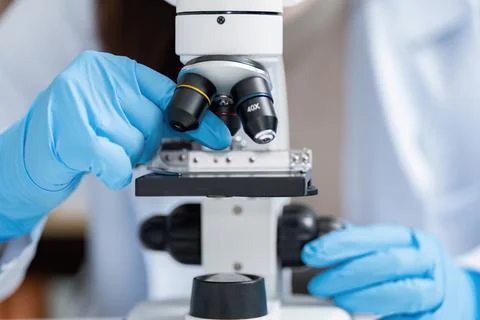 Scientist Using Microscope in Modern Laboratory with Blue Gloves for Scientific Foto stock