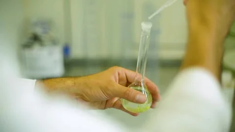 Scientist Using Pipette to Fill Laboratory Flask with Liquid in Laboratory Envir Stock Footage 334054081