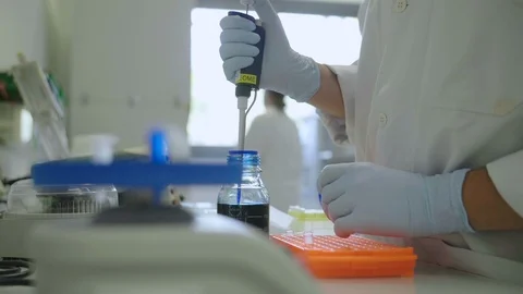 Scientist using a pipette in a laboratory with a centrifuge Stock Footage 96745635