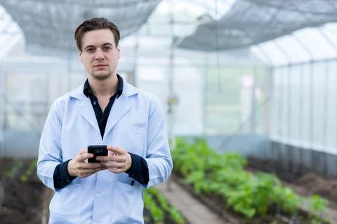 Scientist using Smart Phone. Scientist work at Vegetable Garden Lab site Stock Photos
