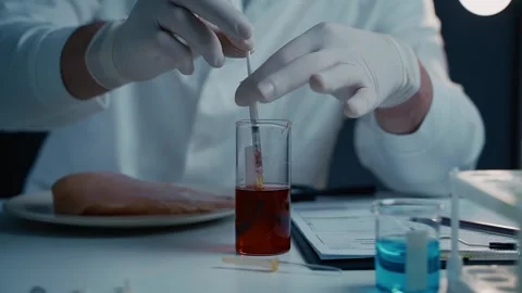 A scientist in a white coat is in a laboratory injecting red liquid into a piece Video stock 297505028