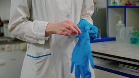 Scientist in a white coat putting on rubber gloves to work in the laboratory Stockbeeldmateriaal 274955463