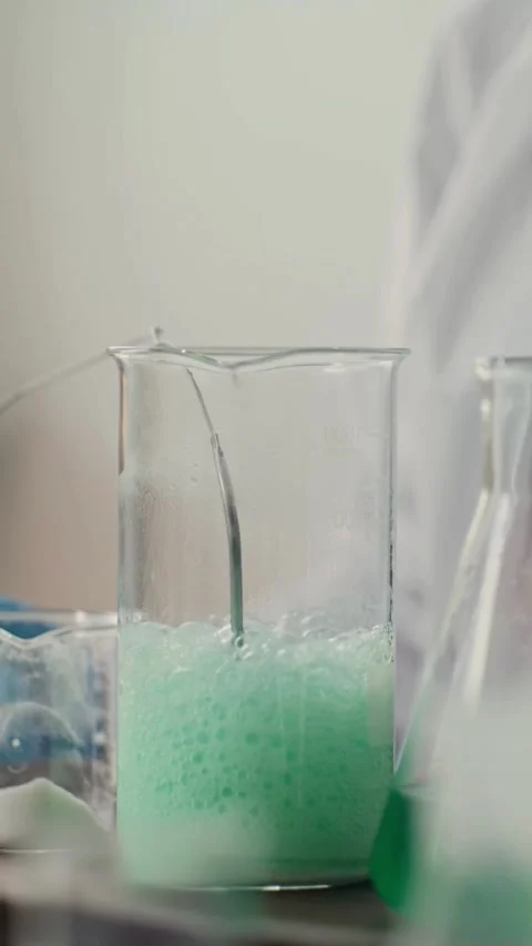 Scientist working with bubbling green liquid in laboratory beaker Video stock 331774937