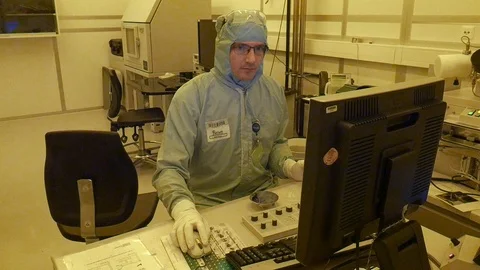A scientist working on a computer handling a big electrone microscope. Vidéo 94569996