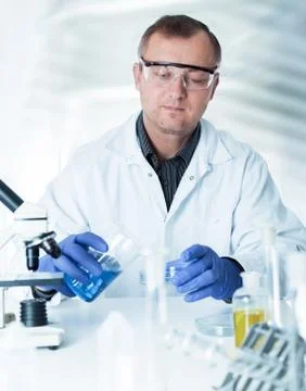 Scientist working in the lab , examines a with liquid Stock Photos