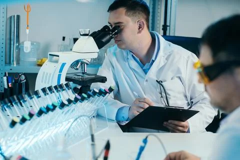 Scientist working with microscope in lab. Laboratory research concept. Stock Photos