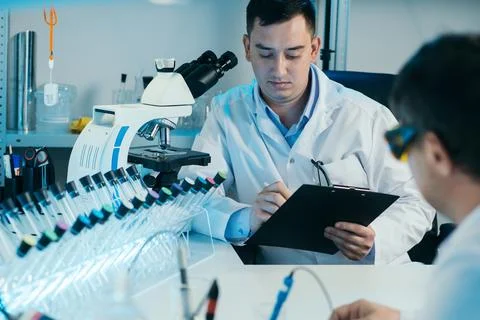 Scientist working with microscope in lab. Laboratory research concept. Stock Photos