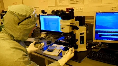 A scientist working with a microscope, looking at microchips. Vidéo 94570036