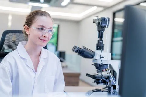 Scientist working at microscope in modern laboratory with digital screens n.. Stock Photos