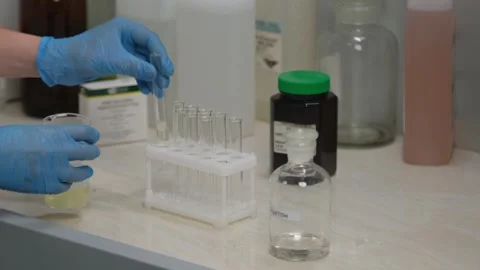Scientist working with test tubes in laboratory, bottle labeled acetone Stock Footage 303369247