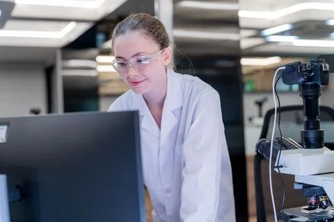 Scientist works at computer in modern lab while analyzing data and wearing .. Foto stock