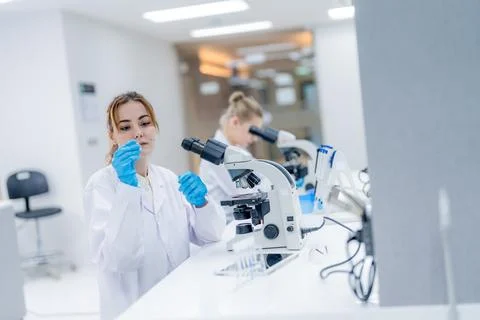 Scientist works in laboratory with microscope while another assistant prepa.. Foto stock