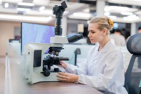 Scientist works in laboratory using microscope to study samples during day Foto stock