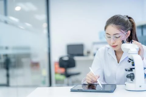 Scientist works in a laboratory using a tablet and microscope during a rese.. Stock Photos