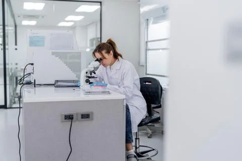 Scientist works at a microscope in a modern laboratory during the daytime w.. Stock Photos