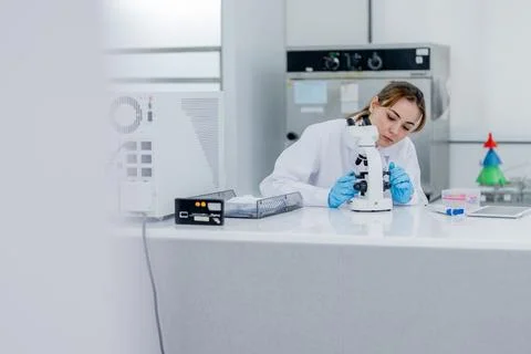 Scientist works at a microscope in a modern laboratory during daylight hours Stock Photos