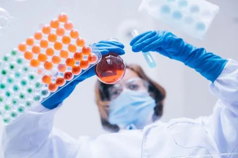 Scientist works with testing tubes wth her gloves on. Stock Photos