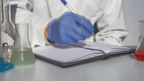 Scientist writes the result to a notebook. Close up. Video stock 118314921