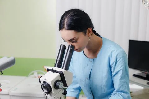 Scientist young woman using a microscope in a science laboratory Stock Photos