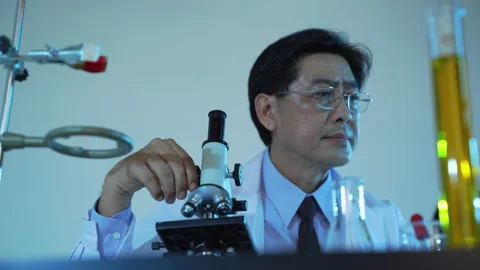 Scientists are shining a microscope to look at a scientific sample Stock Footage 141882140