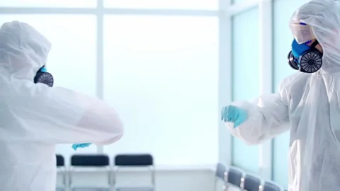 Scientists in biohazard suits salute each other with their elbows. Stock Footage 155390276