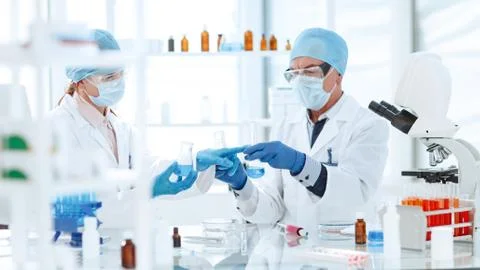 Scientists colleagues checking the liquid in laboratory flasks. Stock Photos