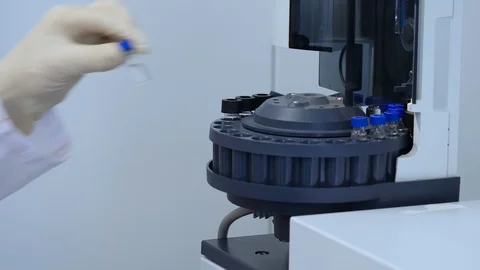 Scientist's hand puts flask with experimental solution in a mixing machine Vídeos de archivo 118063152