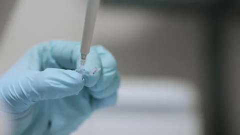 A scientists hands dripping a sample into an eppindorf with pipette. Stock Footage 294344729