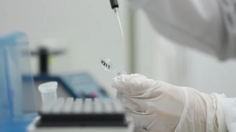 A scientists hands dripping a sample into an eppindorf with pipette. Stock Footage 294355976