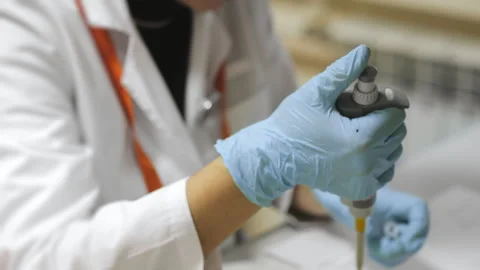 A scientists hands dripping a sample into an eppindorf with pipette. Stock Footage 294535116