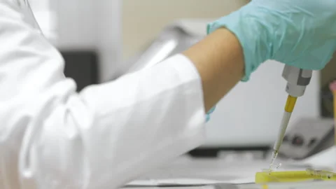 A scientists hands dripping a sample into an eppindorf with pipette. Stock Footage 294536421
