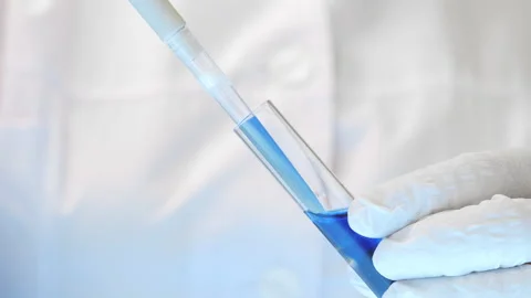 A scientists hands taking a sample of blue liquid from a test tube Stock Footage 302174331