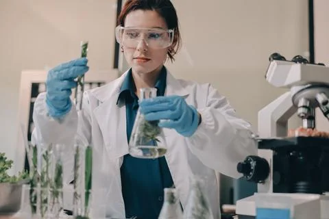 Scientists in lab coats work with plants in a modern lab, focusing on resea.. Stock Photos