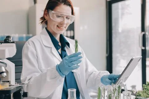 Scientists in lab coats work with plants in a modern lab, focusing on resea.. Stock Photos