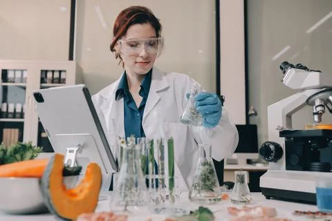 Scientists in lab coats work with plants in a modern lab, focusing on resea.. Stock Photos