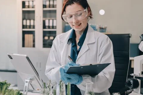 Scientists in lab coats work with plants in a modern lab, focusing on resea.. Stock Photos