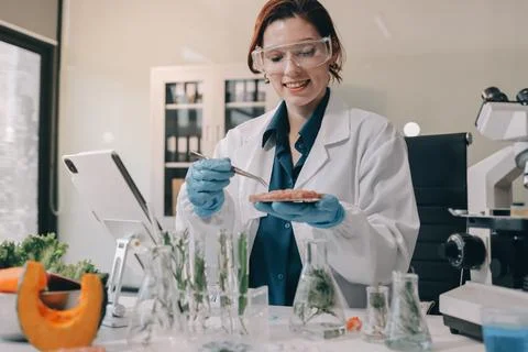 Scientists in lab coats work with plants in a modern lab, focusing on resea.. Stock Photos