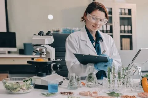 Scientists in lab coats work with plants in a modern lab, focusing on resea.. Stock Photos